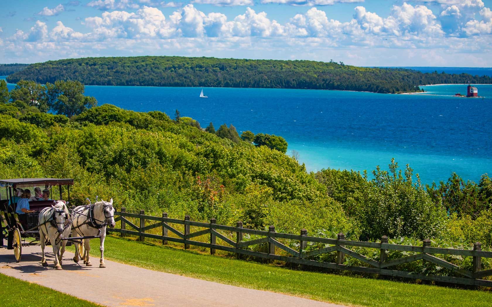 A horse-drawn carriage down a road in front of Lake Superior.