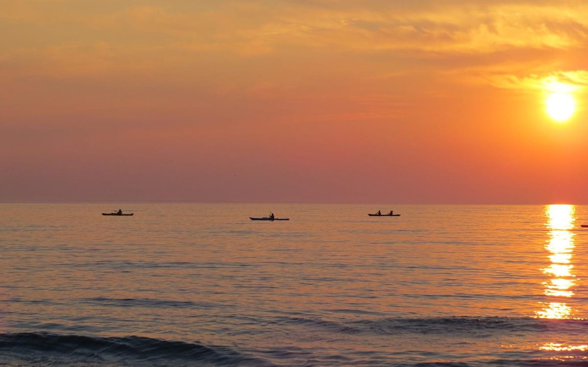 Boats and kayaks on Lake Michigan at sunset.
