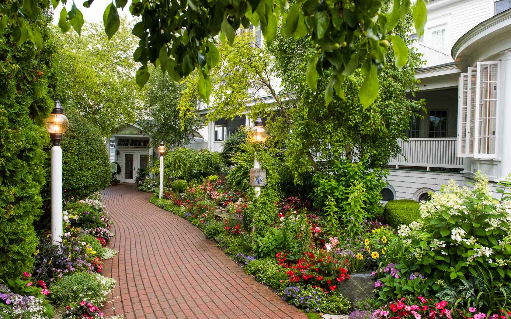 A brick path with beautiful garden on either side leading to the inside of Hotel Iroquois.