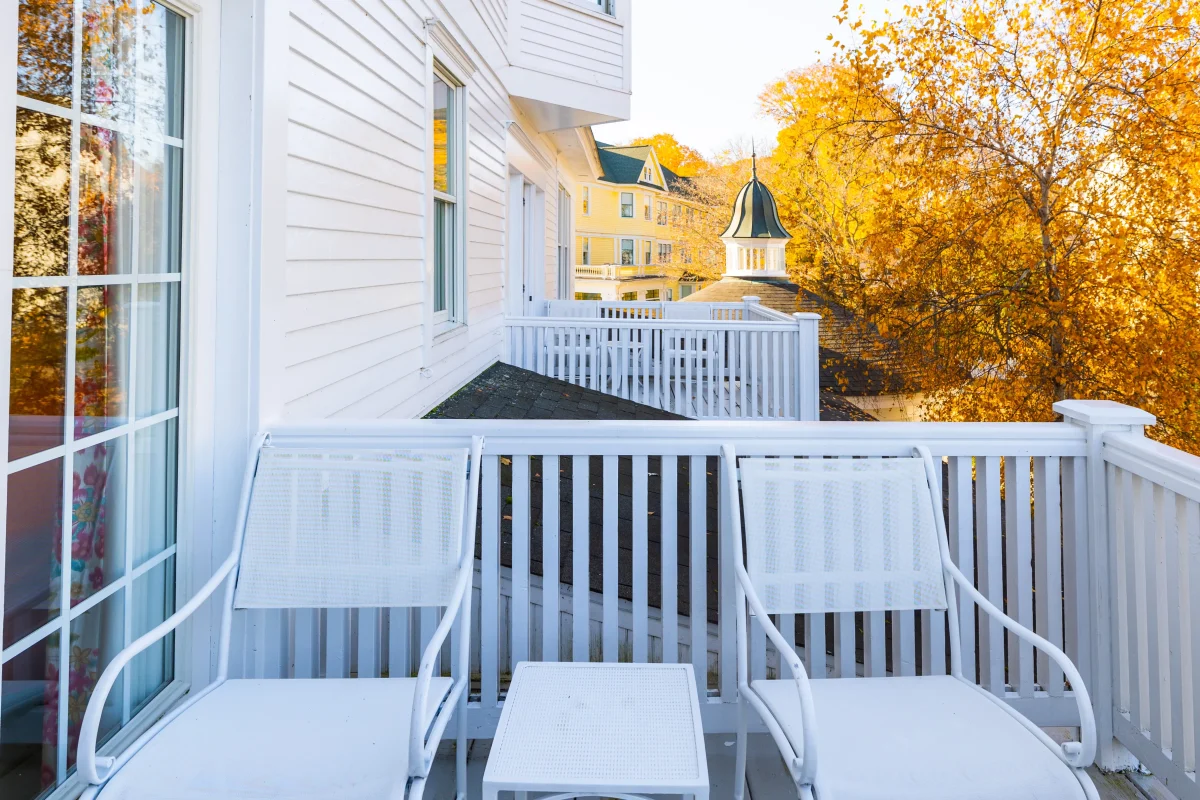 balcony with chairs looking out at a tree in the fall.