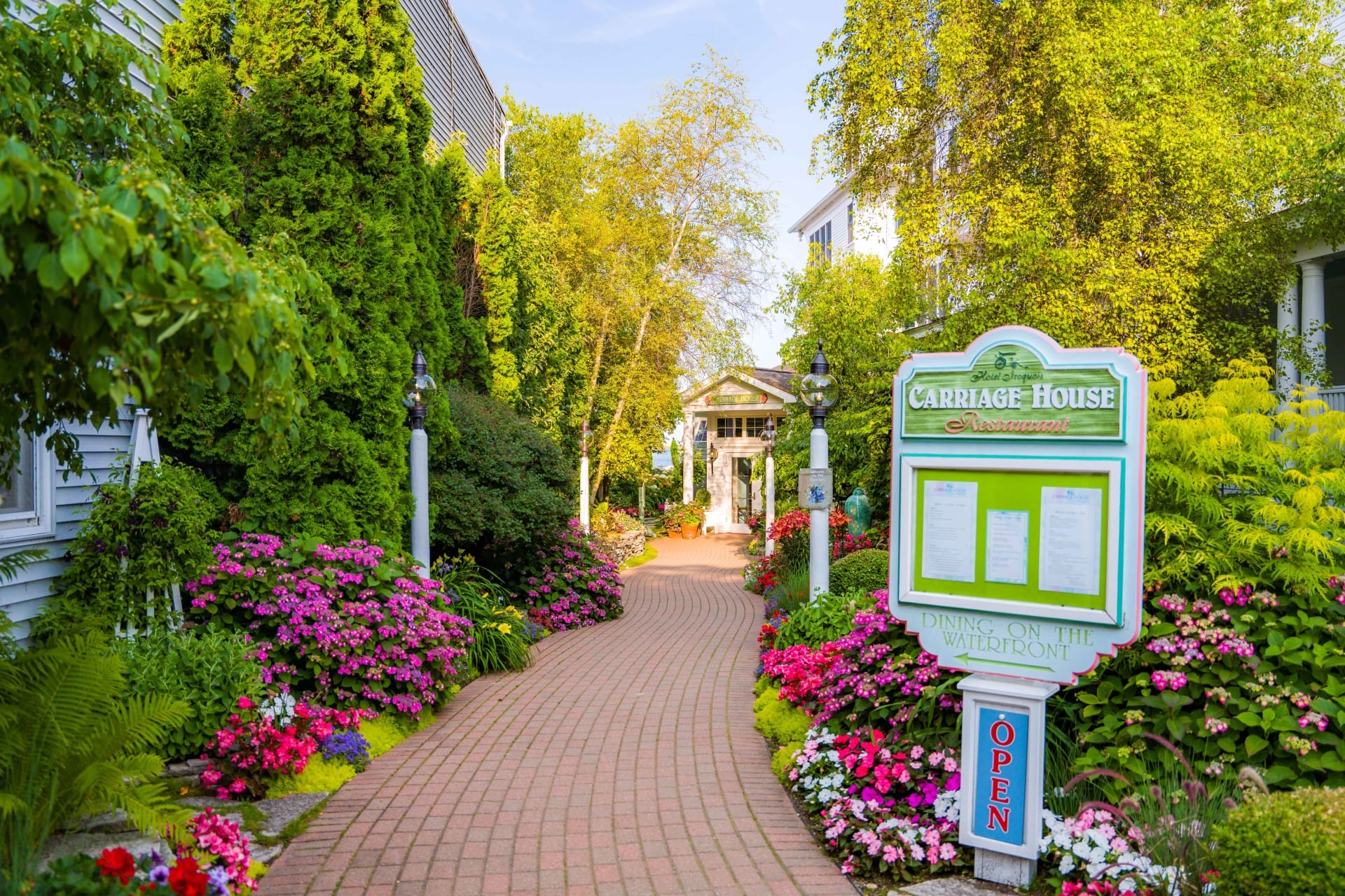 A stone walkway through beautiful garden on either side of flower and tree.