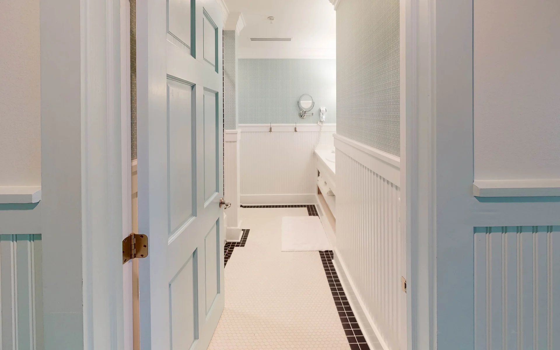 A white bathroom with view of a blue door.
