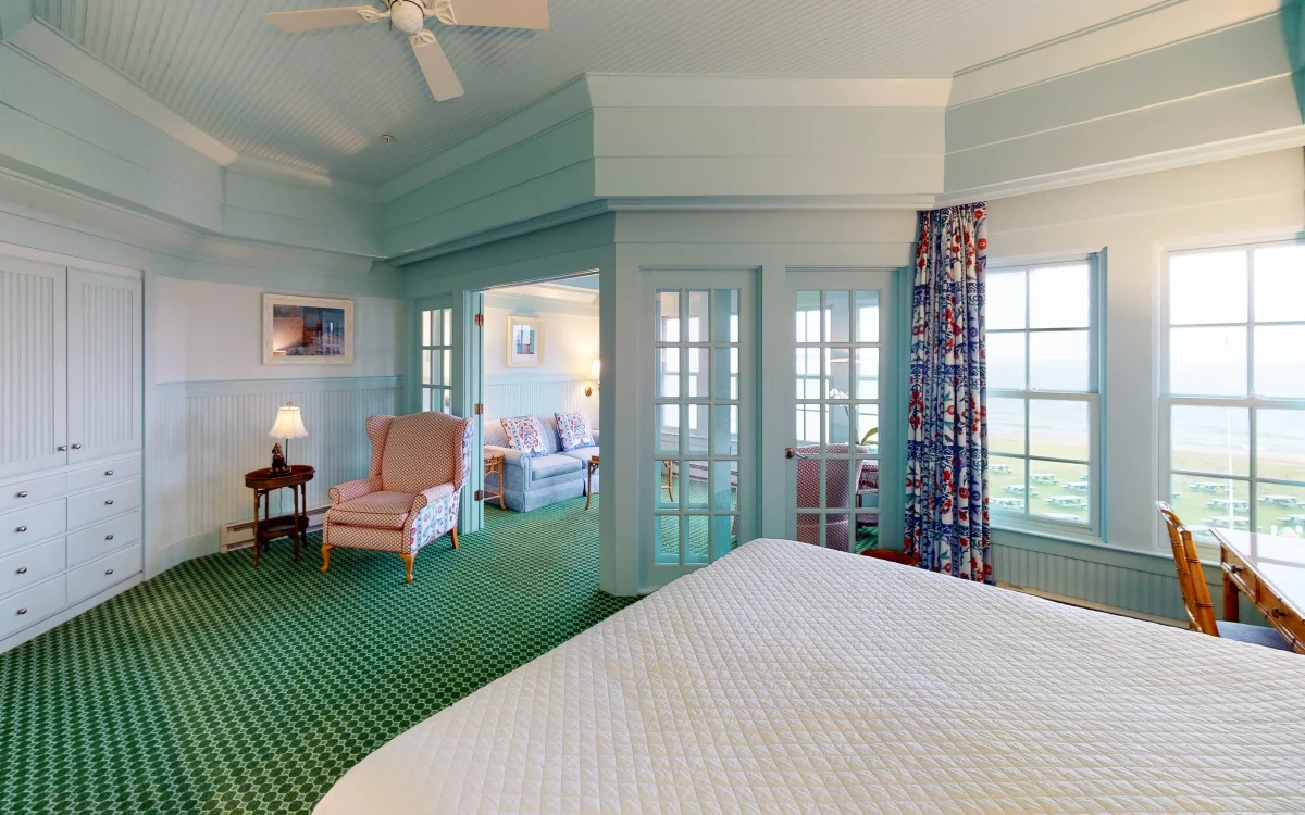 A green carpeted room with view of a chair and seating room with lots of windows.