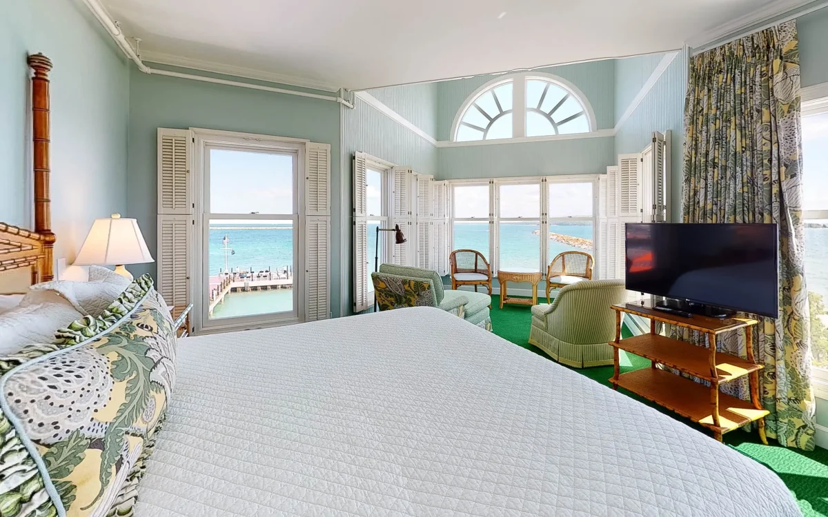 A white bed looking out onto Lake Superior through windows.