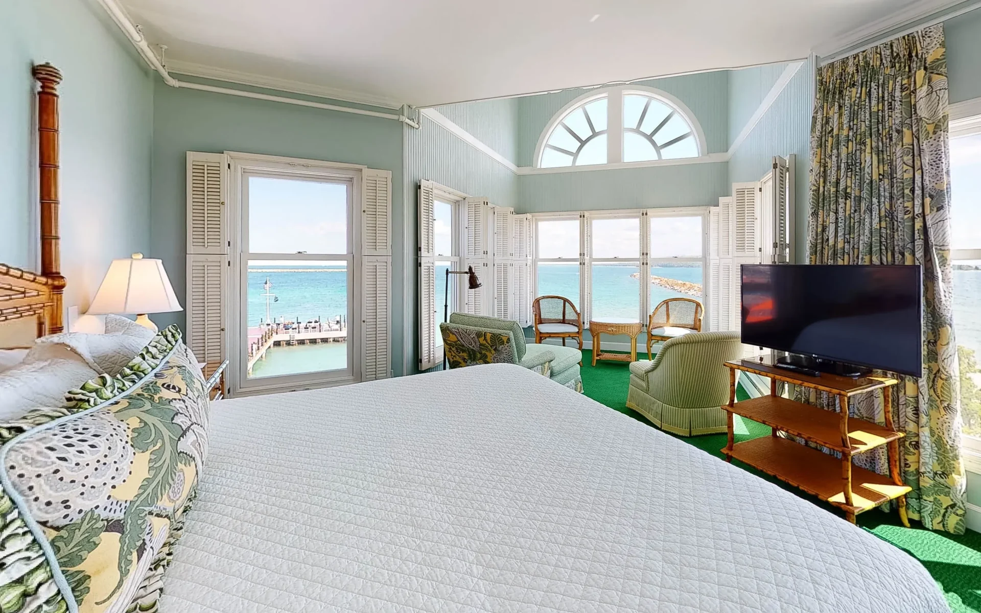 A white bed looking out onto Lake Superior through windows.