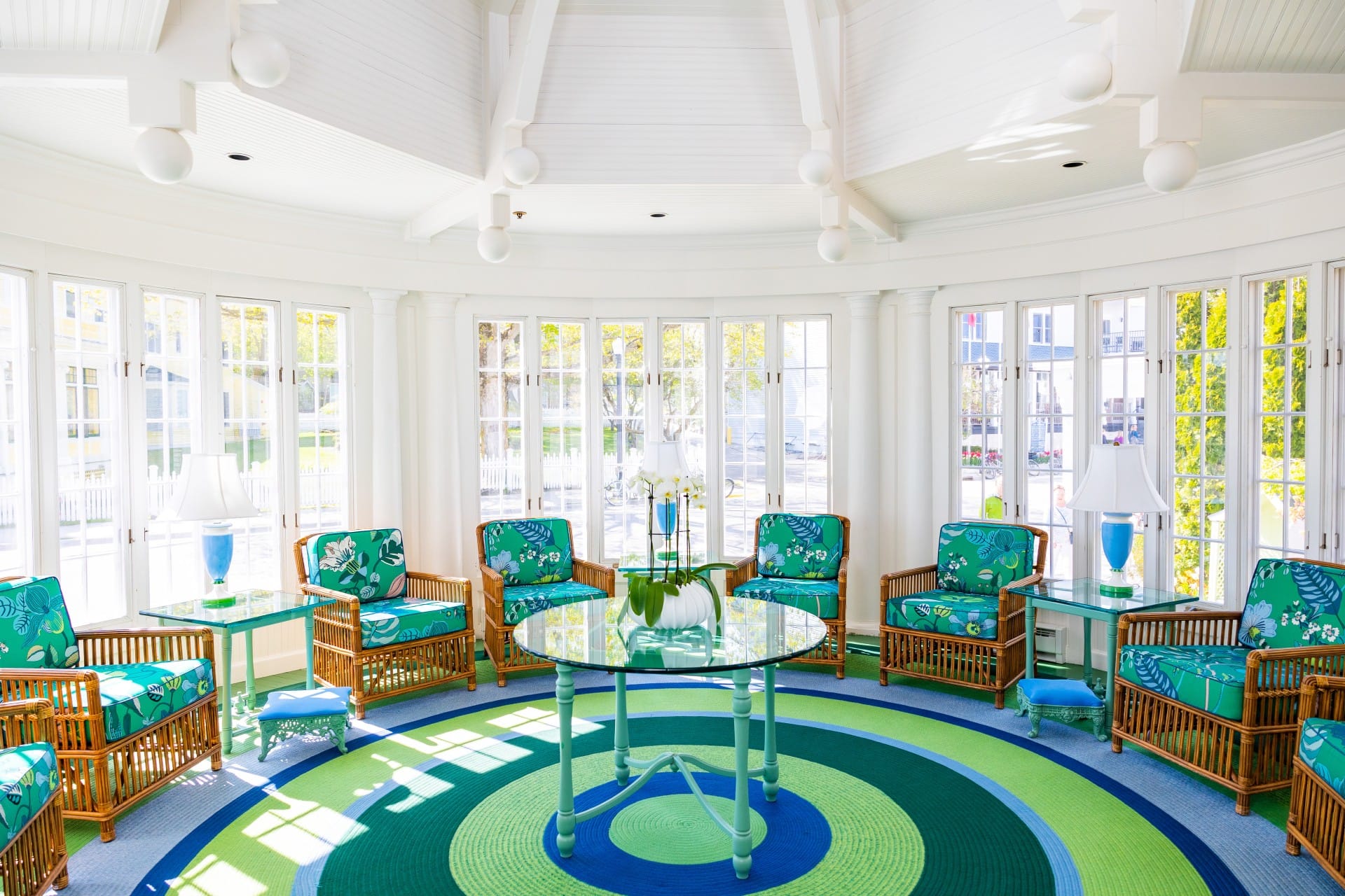 A sitting room with many windows and green chairs.