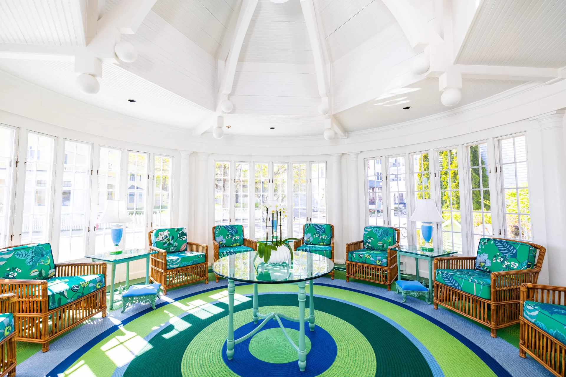 a sitting room with lots of w light coming in with white walls, green carpet, and green chairs.