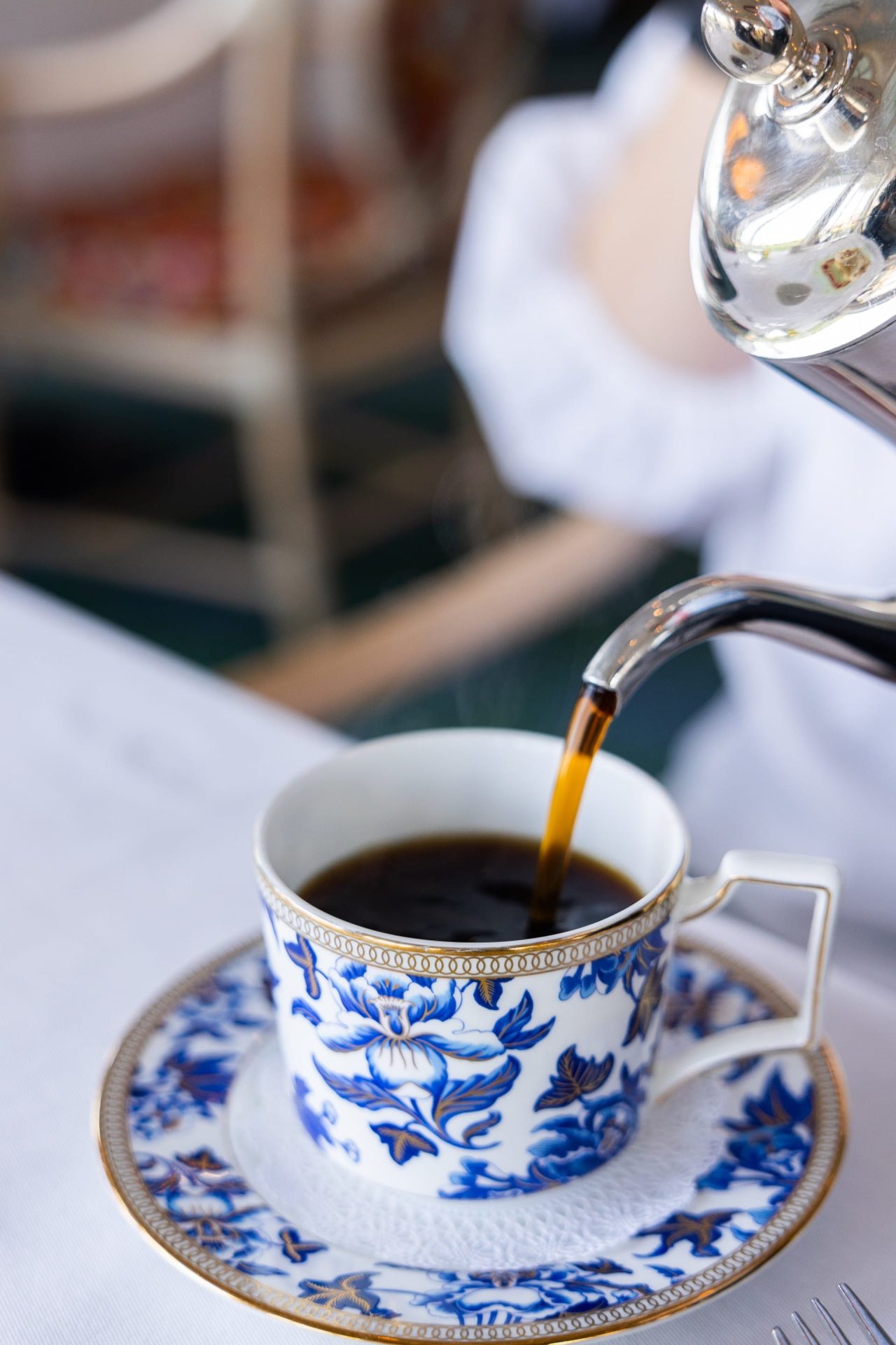 Coffee being poured into a blue saucer and cup.