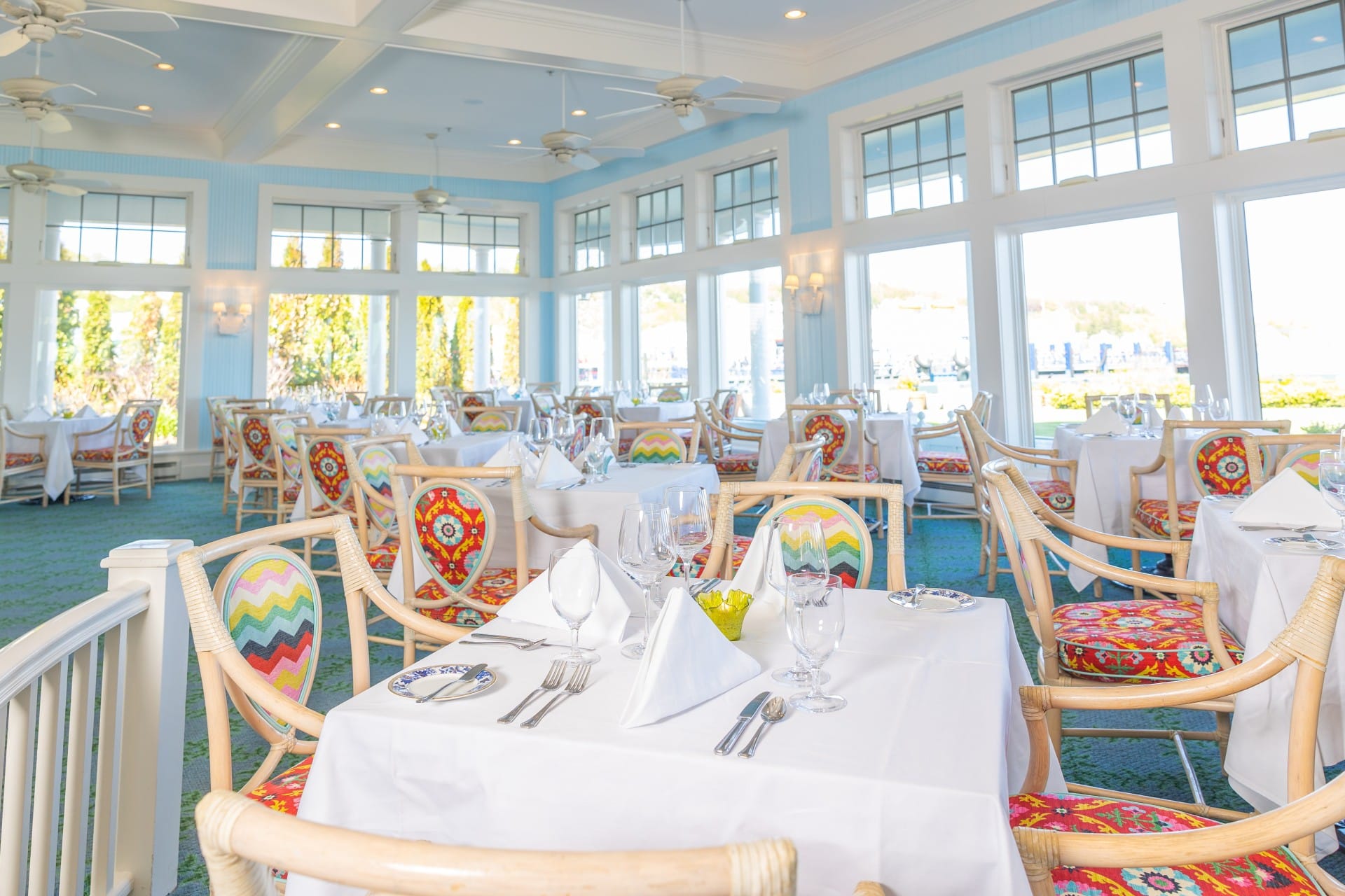 Indoor dining in a blue room with many windows, tables, and chairs.