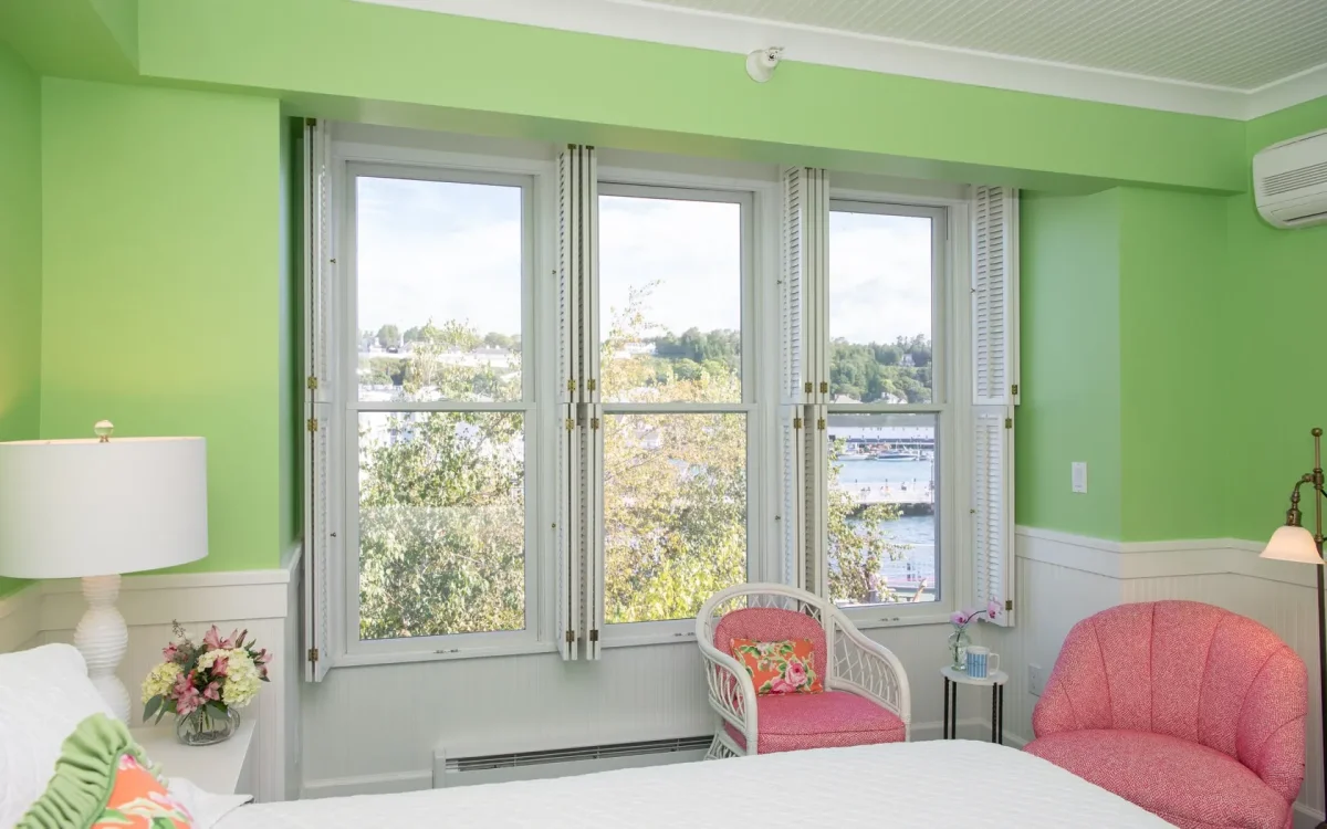 A green room with windows and a chair.