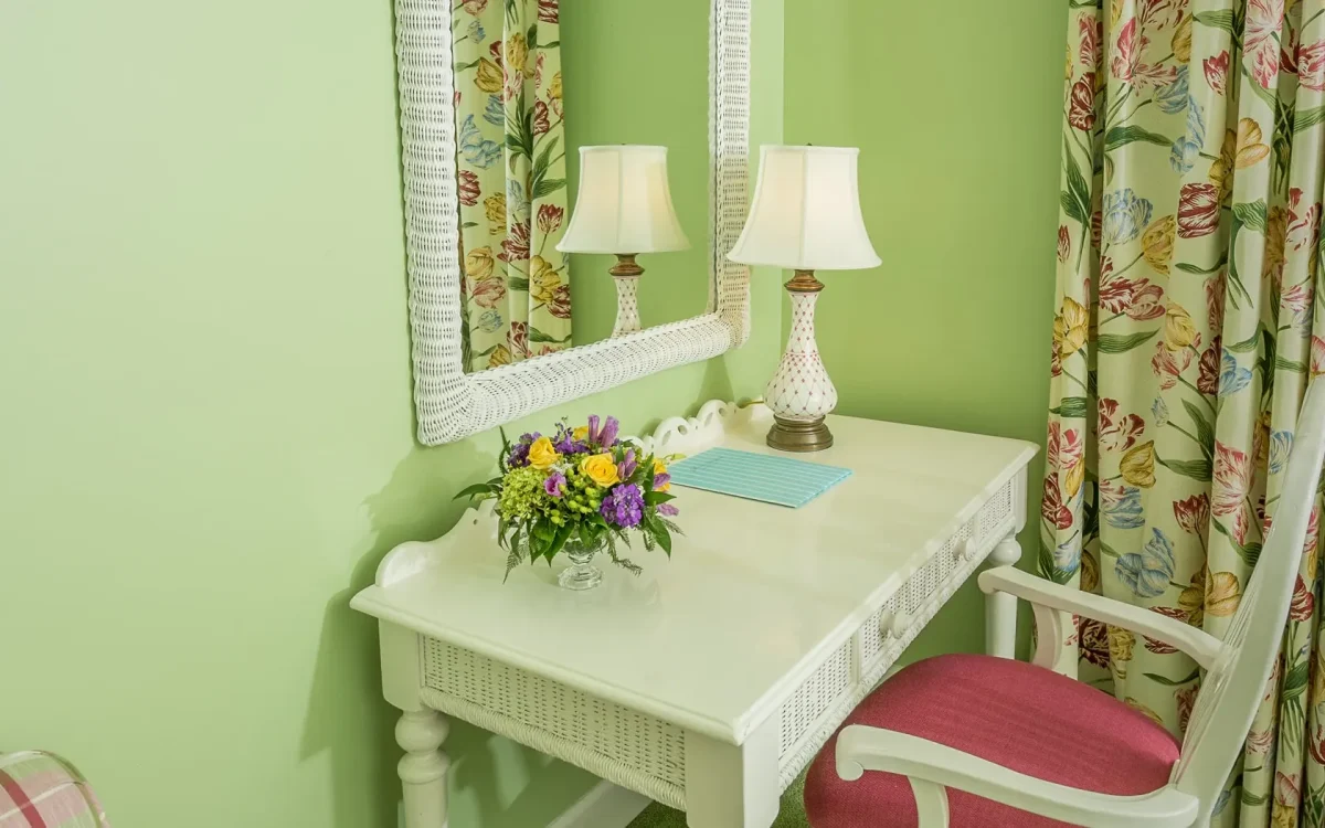 A desk with a red chair looking onto a mirror.