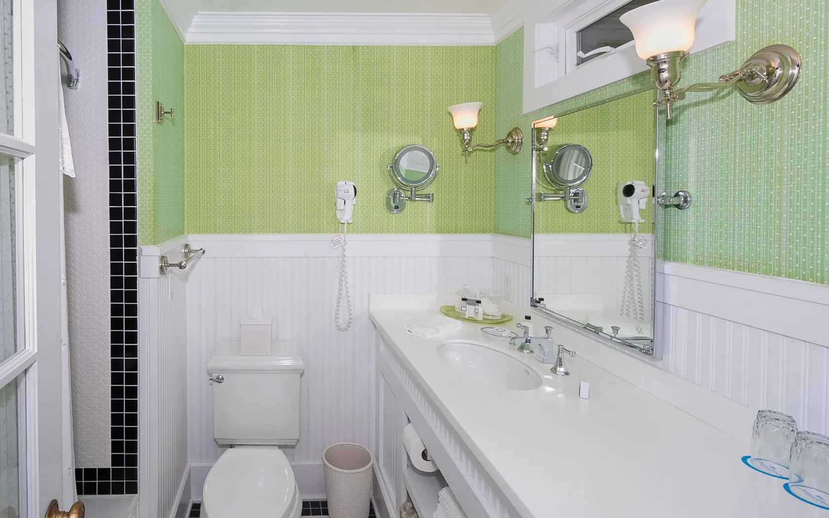 A green and white bathroom with view of the toilet and sink.
