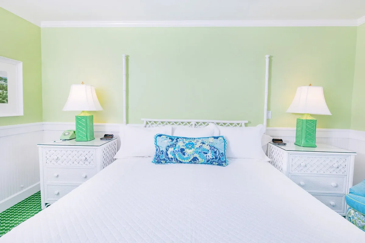 A white bag with blue accent pillow and a green room with green lamp.