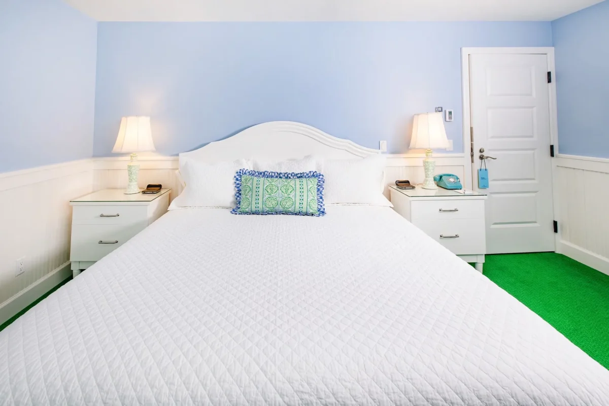 A white bed and a blue room with cream accent pillow.