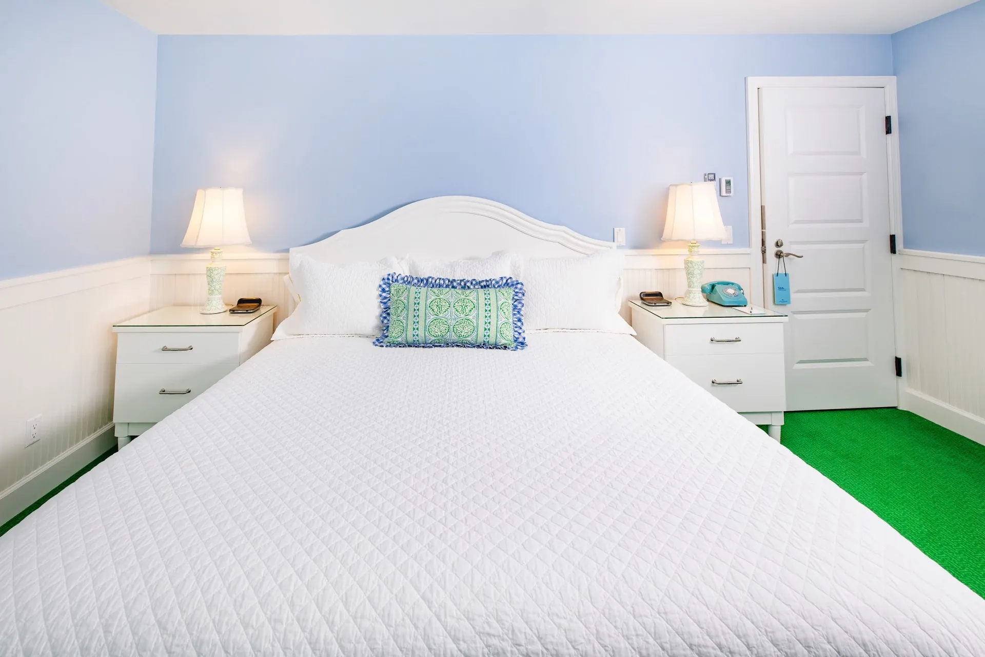 A white bed and a blue room with cream accent pillow.