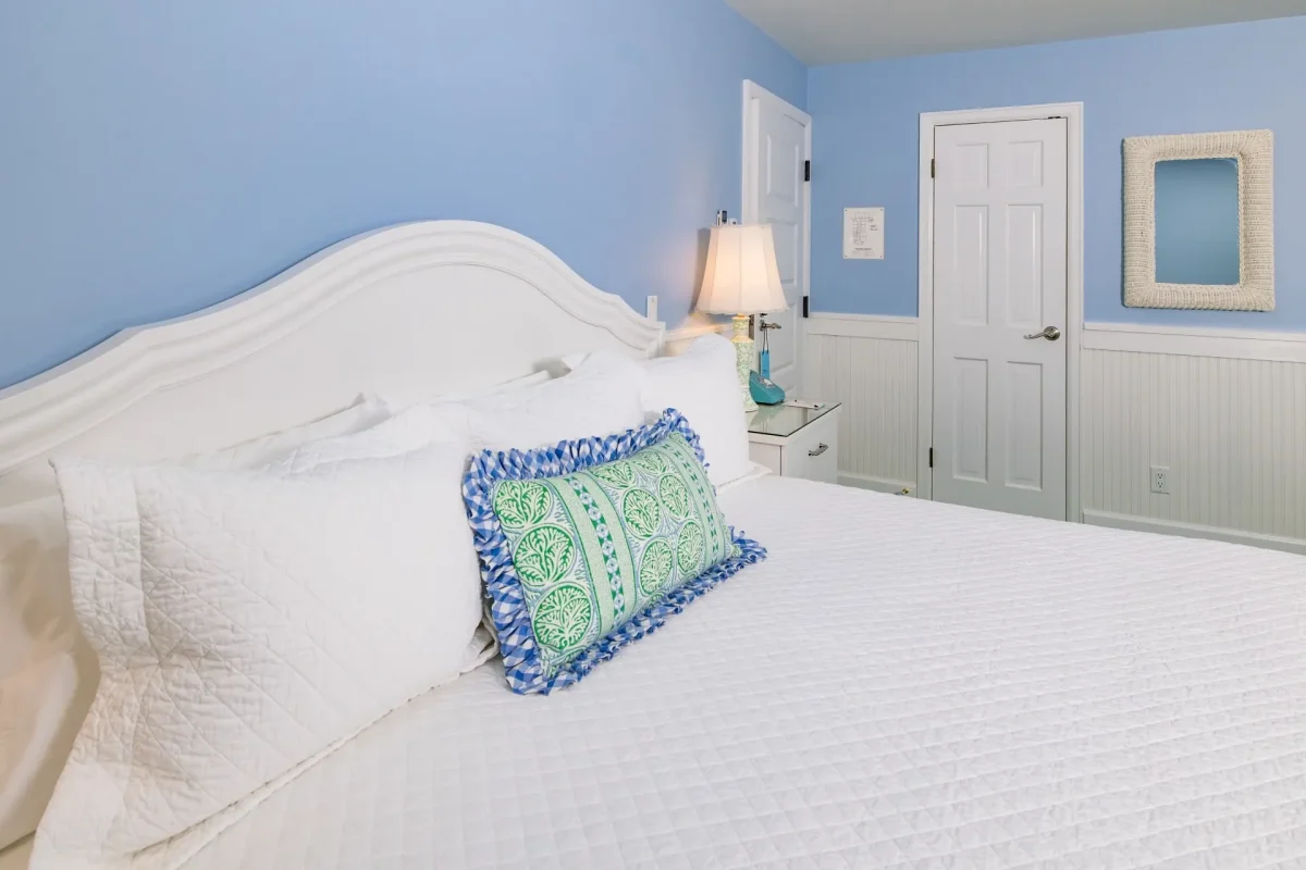 White bed and a blue room with accent pillow.