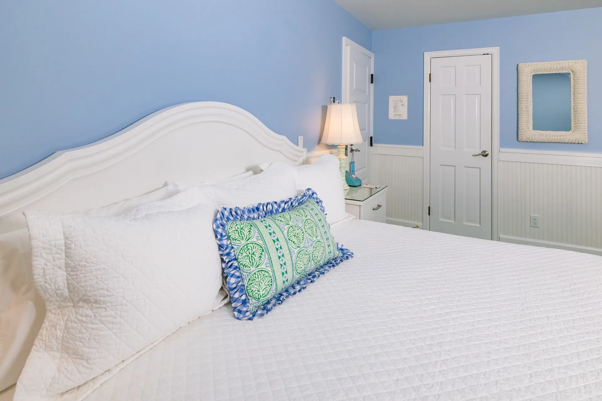White bed and a blue room with accent pillow.