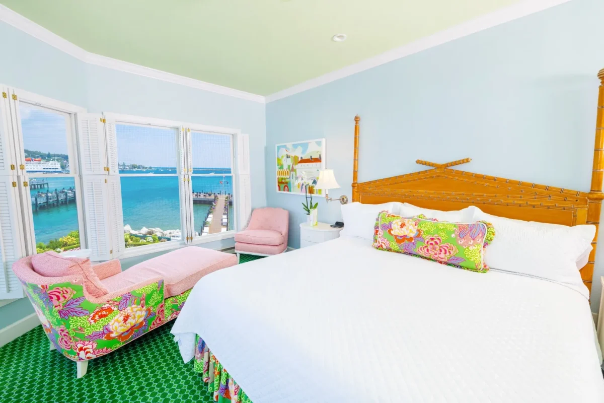 White bed in a blue room with green carpet with lots of windows.
