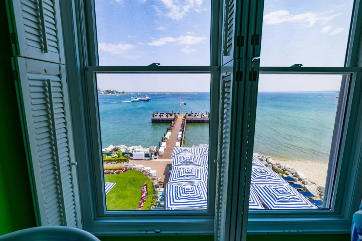 A window with blue shutters looking out onto a dock.