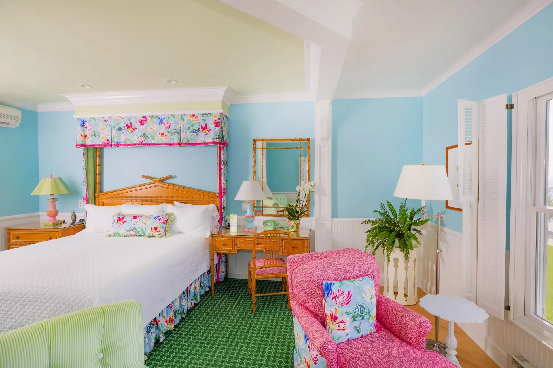 White bed in a blue room with lots of windows and green carpet.