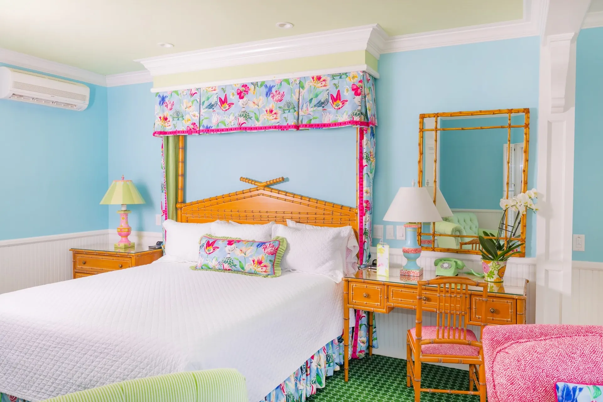 White bed in a blue room and green carpet with accent curtains.