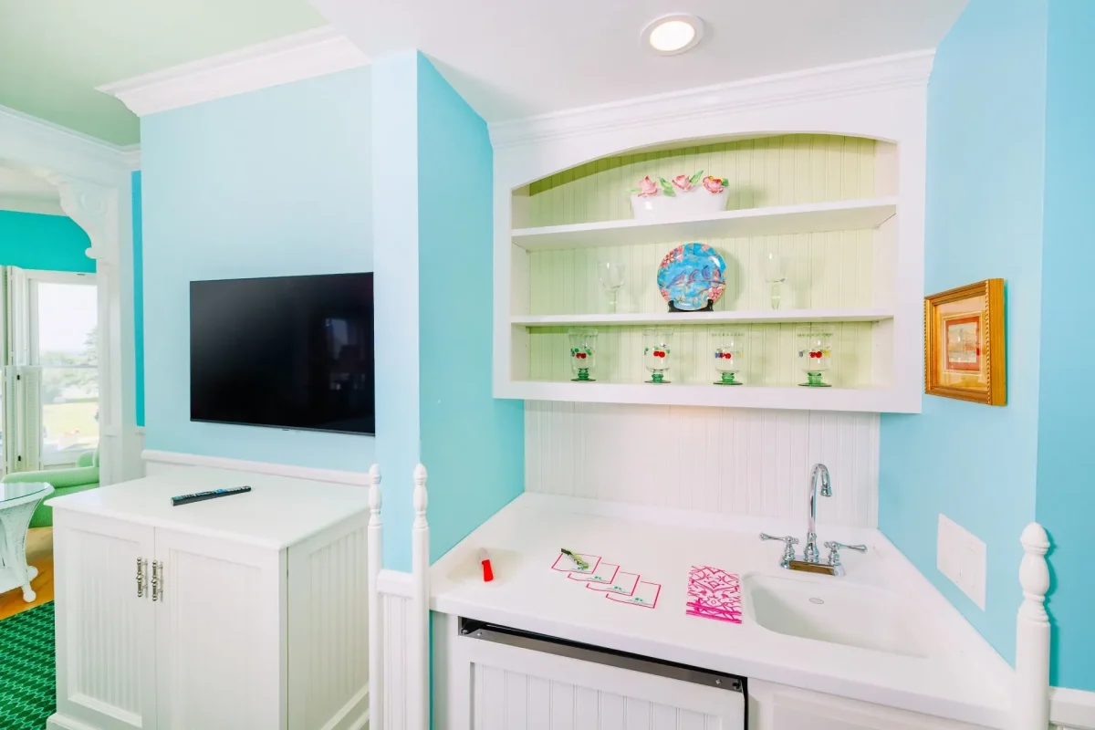 White kitchenette with blue walls and television.