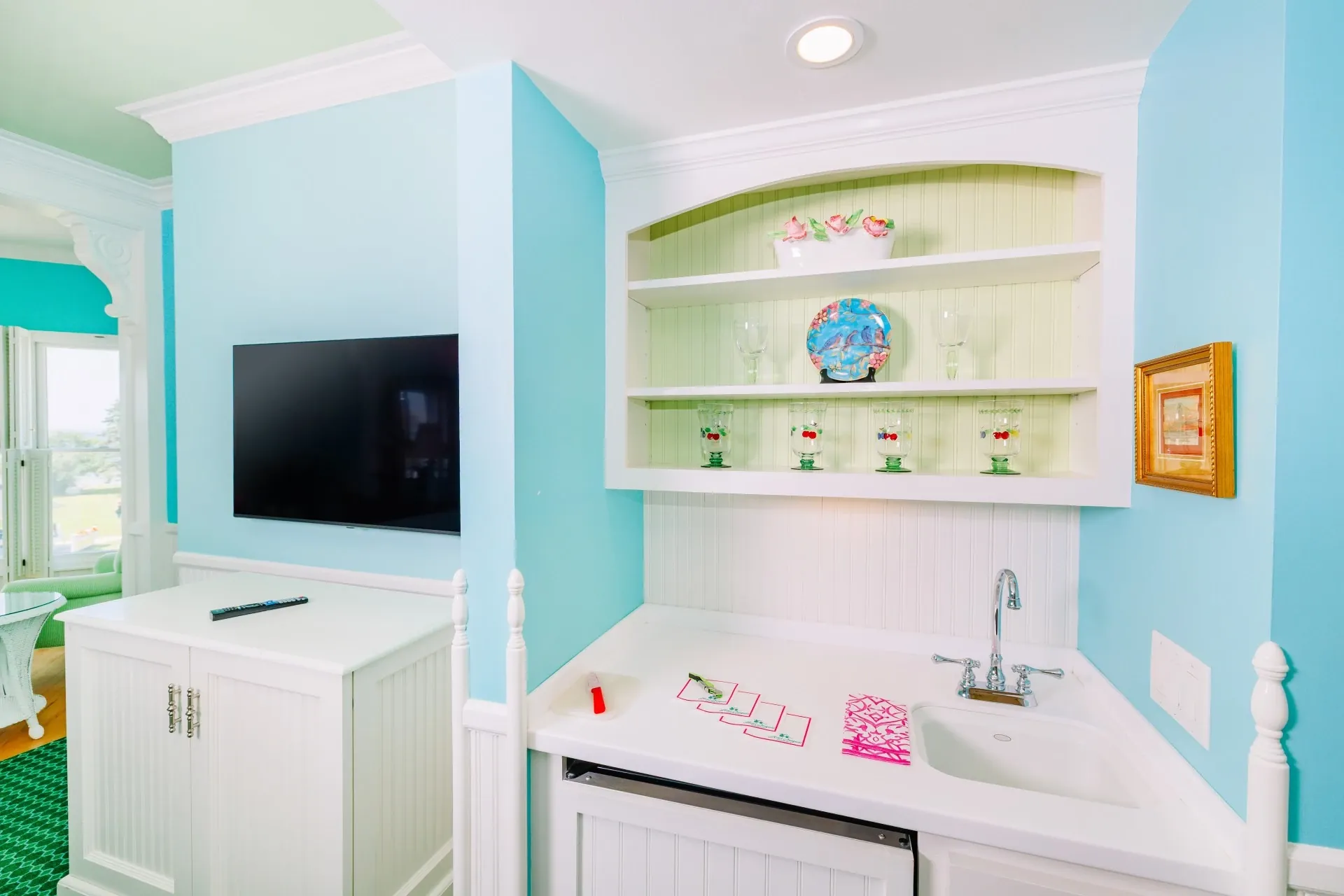 White kitchenette with blue walls and television.