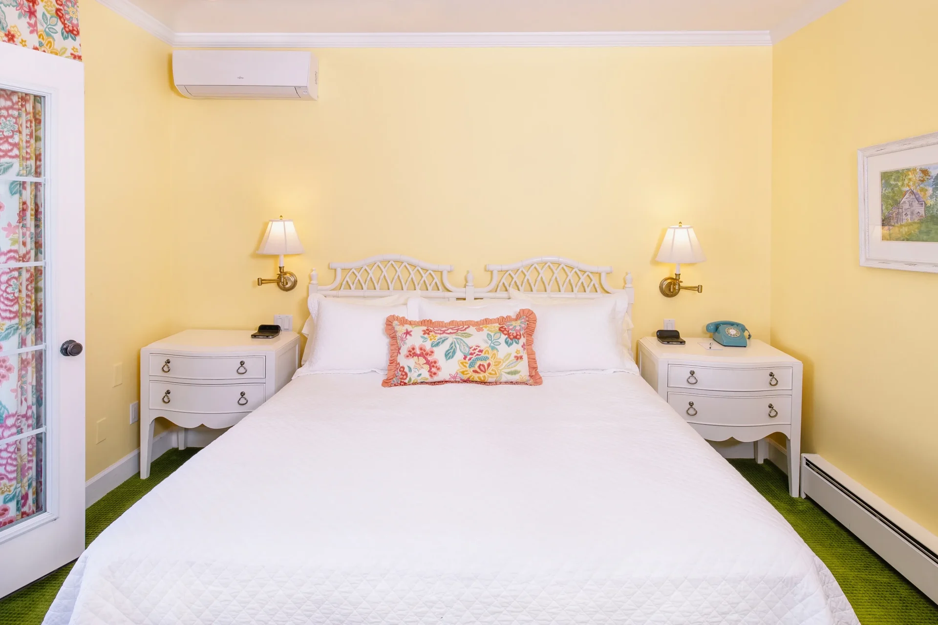 A white bed and an orange room with an accent pillow with lighting on either side.