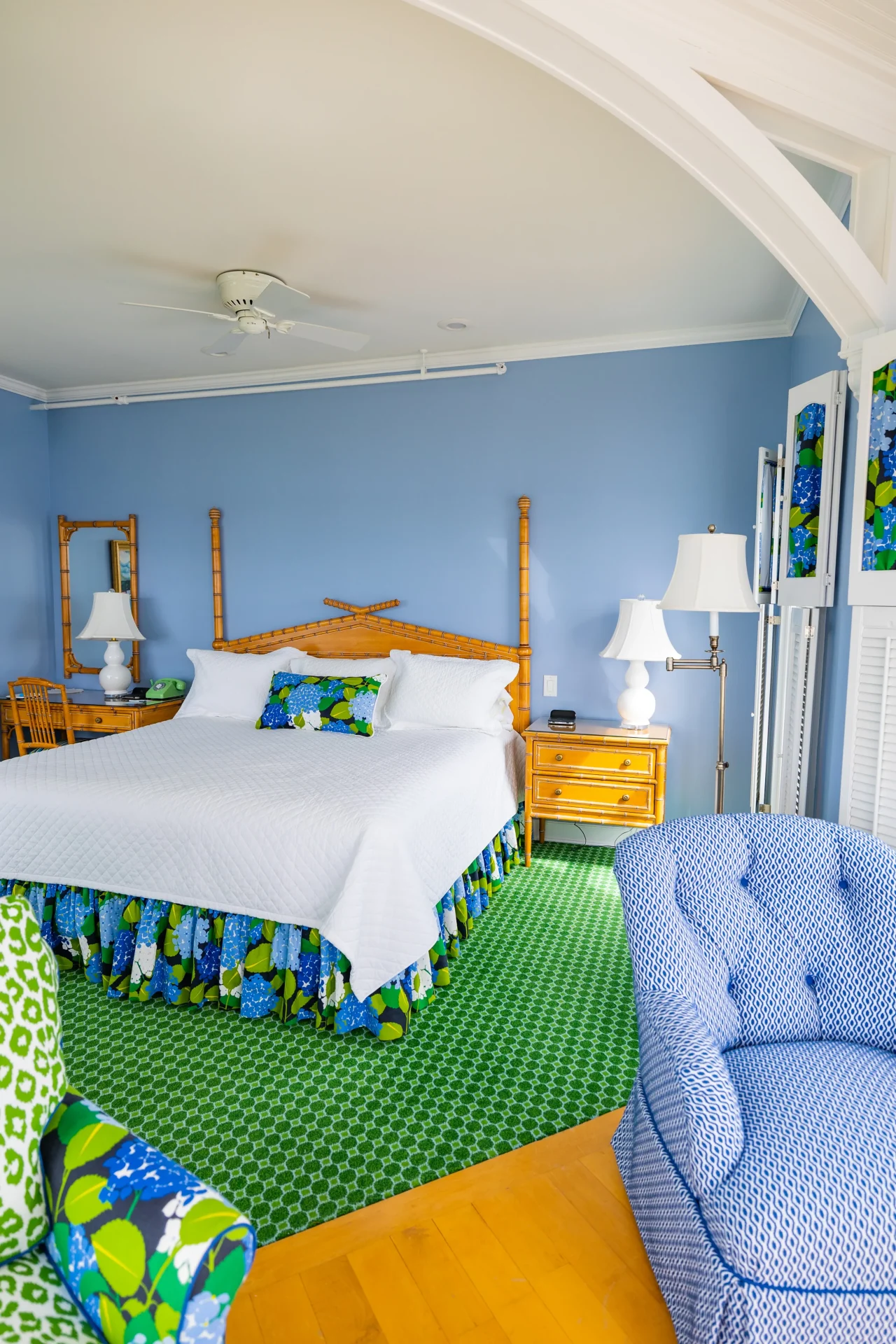 A white bed with brown wooden frame and a green carpet room with blue walls.
