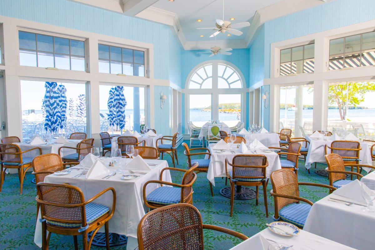 A restaurant dining area with blue walls, lots of windows, and many tables and chairs.