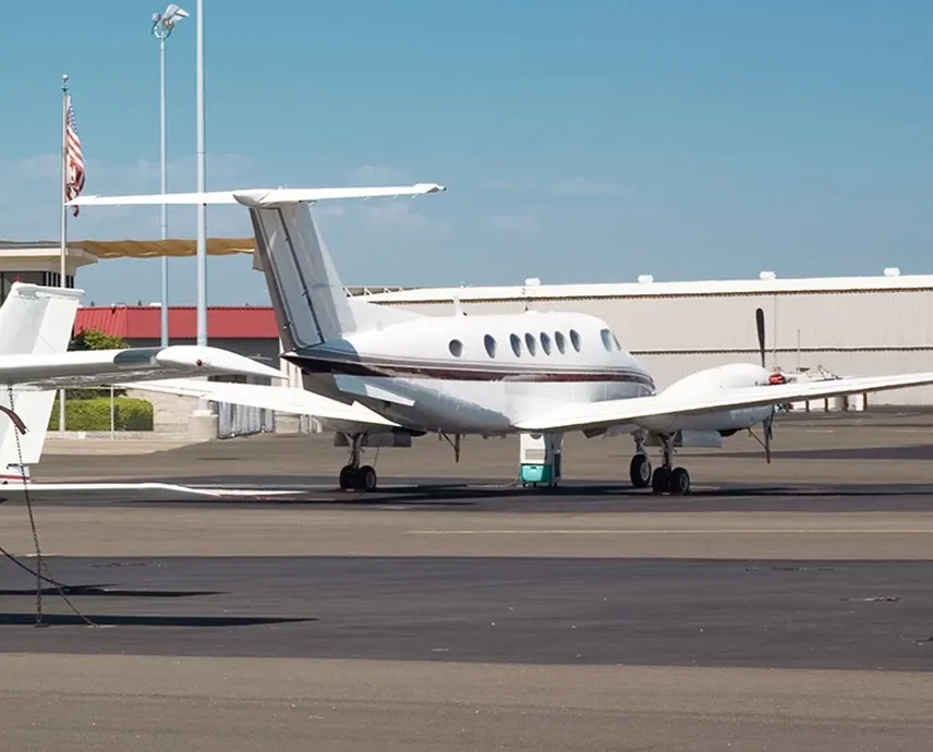 A white plane on a runway in front of a building.