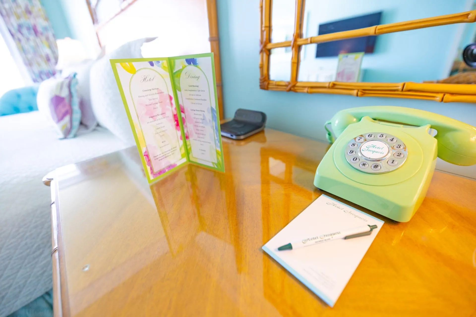 A wooden table with a phone, notepad, and menu.